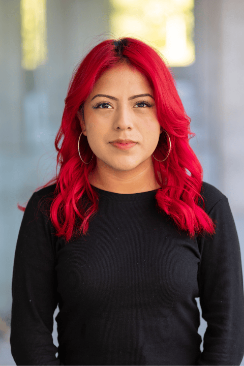 A person with red shoulder length hair smiling