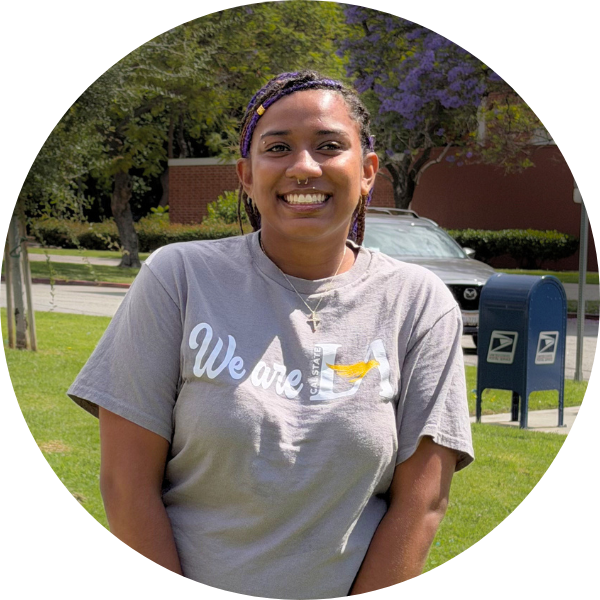A woman with braids and a nose piercing smiling with a grey t-shirt.