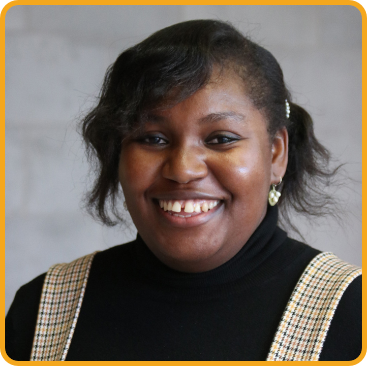 Headshot of Nene Ogbechie. She is smiling and wearing a plaid dress over a black turtleneck