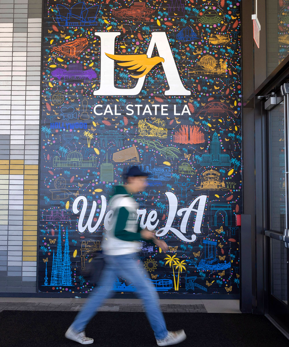 A person walking in front of a mural.