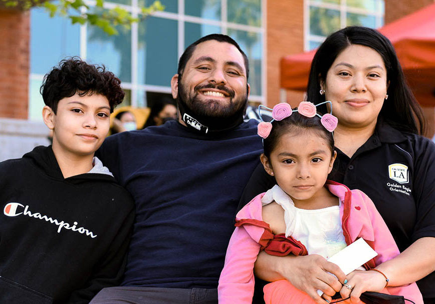 Two parents sitting with their small children, smiling.