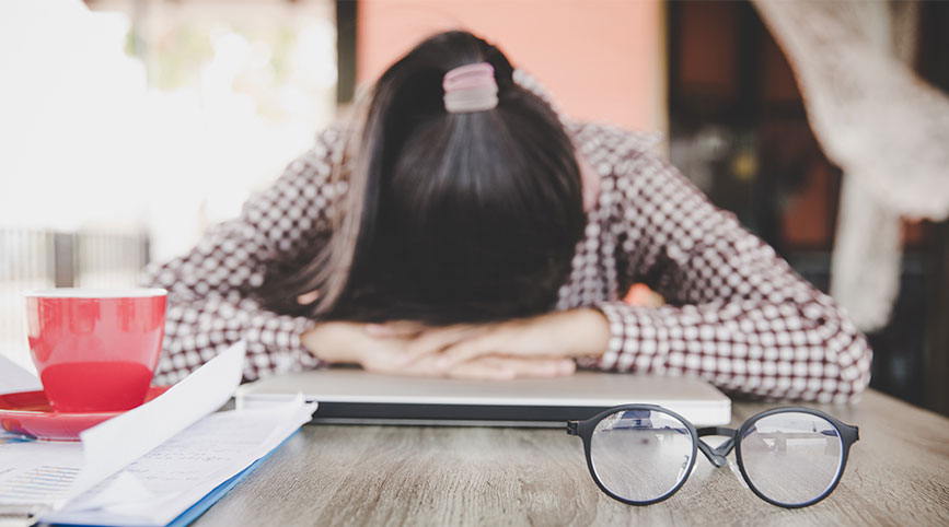 A female person has her head on her desk in frustration