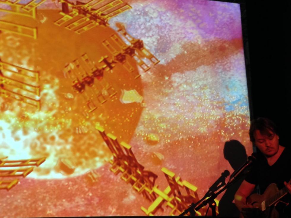 Jim Ovelmen performing live music in front of his projection work "Western Skies".