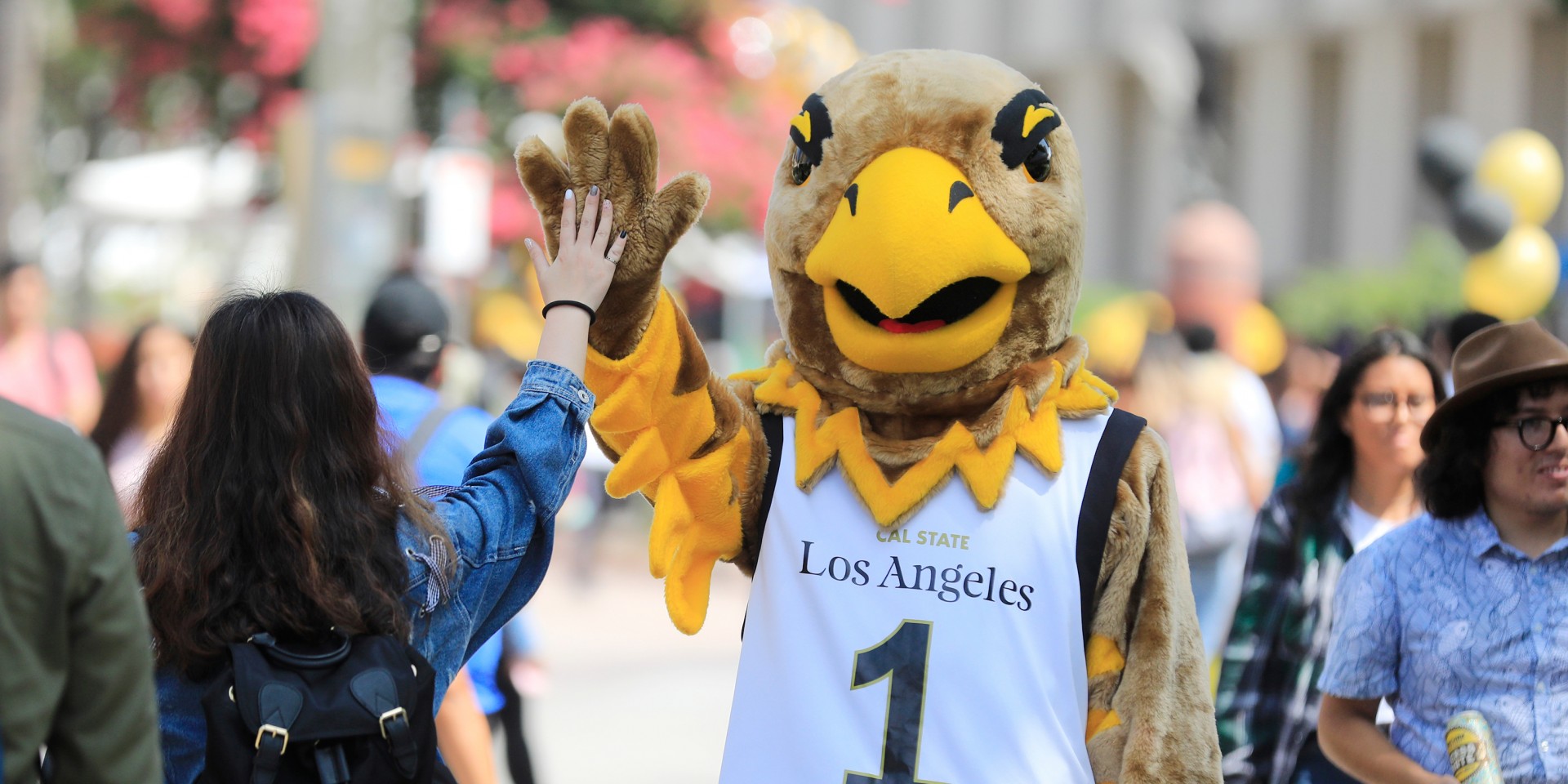 Eddie the Golden Eagle high-giving a student on the Main Walkway.