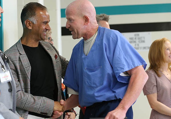 Bidhan Roy, Ph.D. shaking hands with inmate