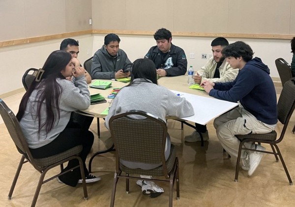 Students seated and talking at a roundtable.