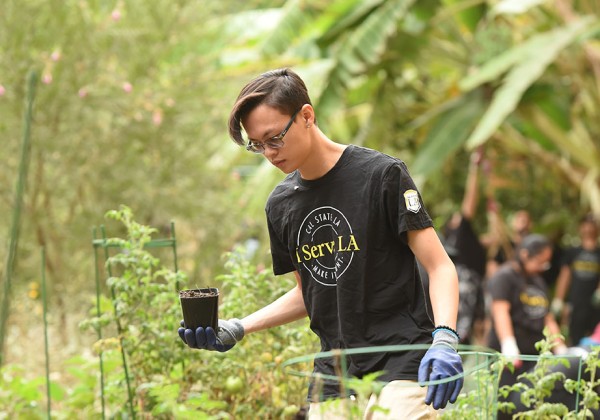 Student holding a small potted plant.