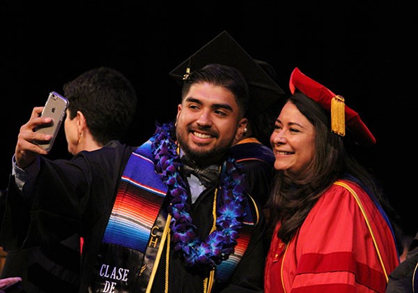 A graduate takes a selfie with a professor