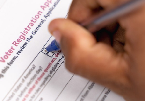 A person filling out a form to register to vote.