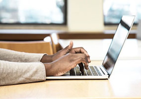 student typing on laptop