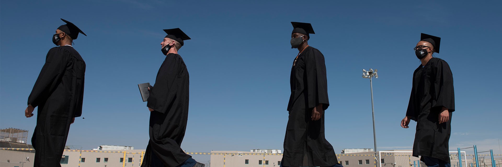 4 incarcerated individuals walking to graduation ceremony