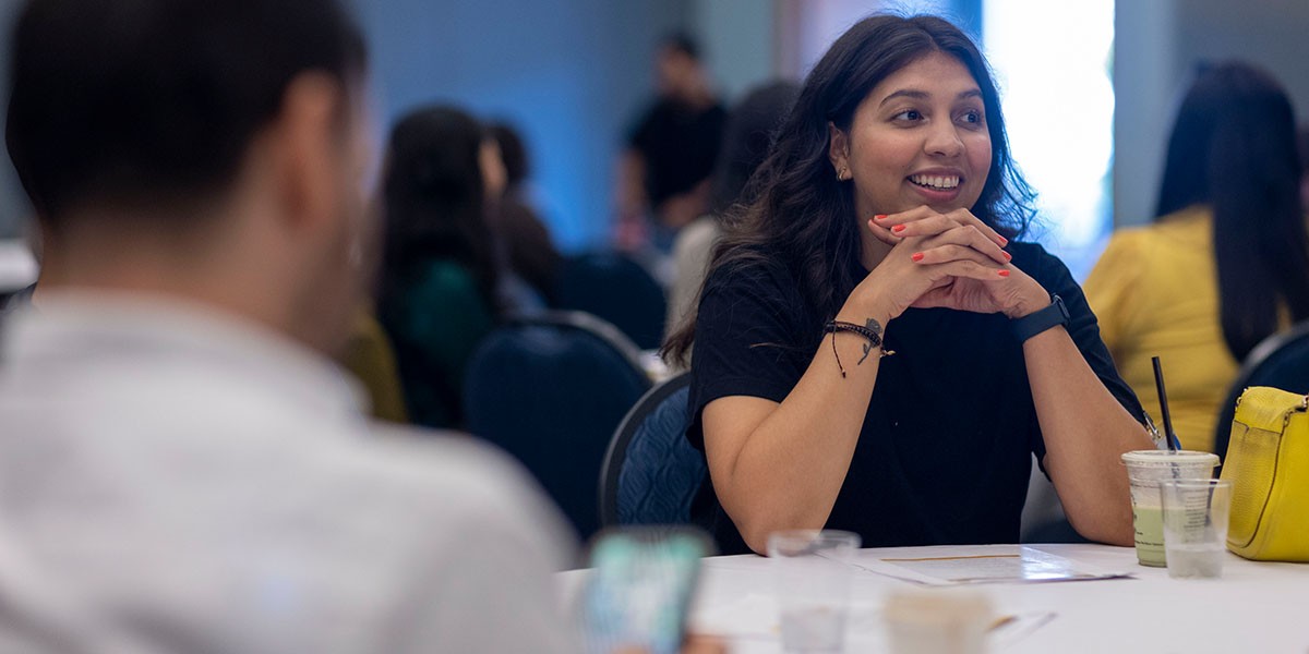 New Faculty member sitting at round table and engaged in a discussion with other people at table.