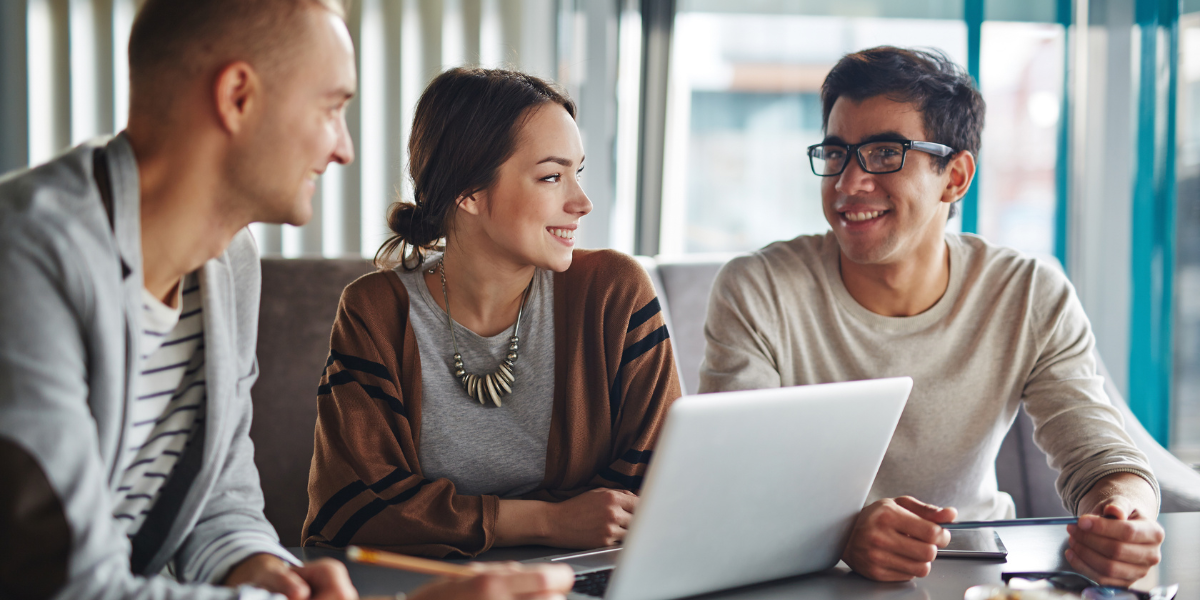 3 people in office conversing at desk