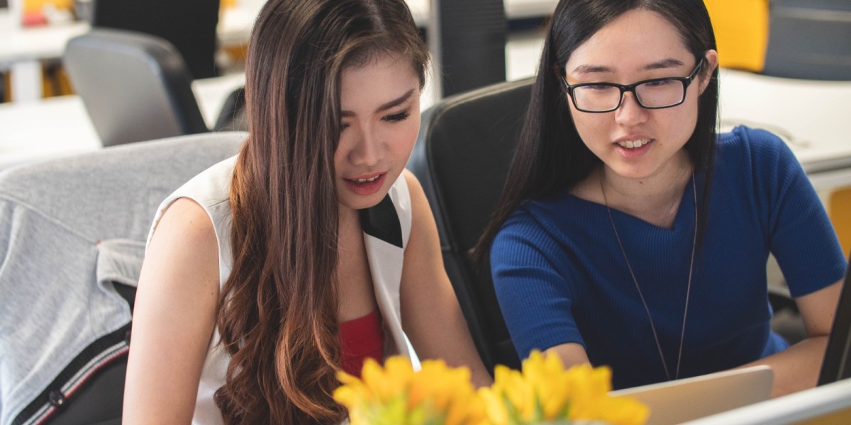 two women discussing content on laptop