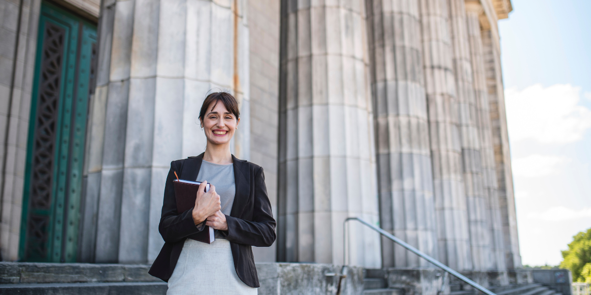 Woman holding a notebook in front of a courthouse.