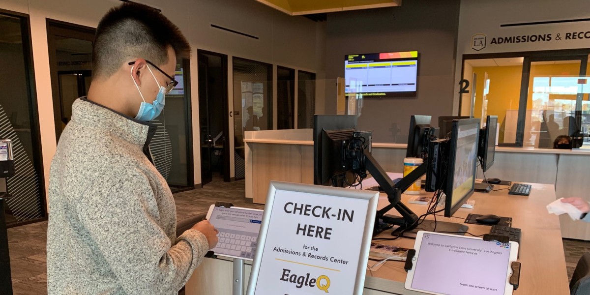 Image of the visitor check-in Kiosk. A student is tapping the screen to begin the process