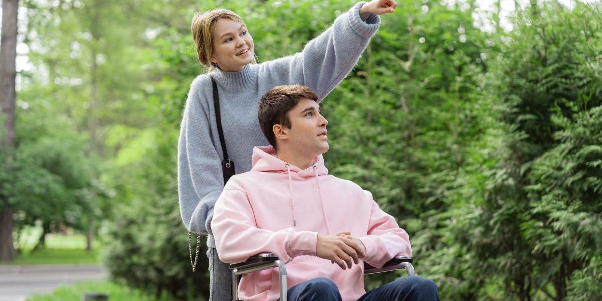 woman wheeling man through park