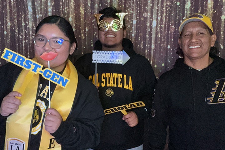 Three people holding up props and smiling.