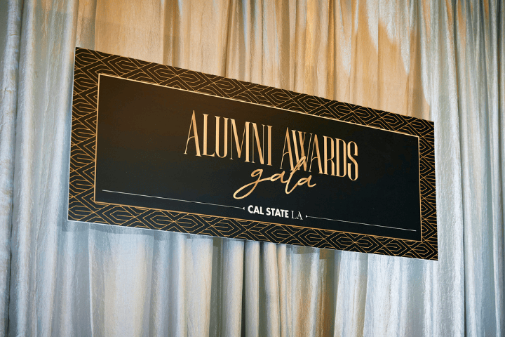 Black and gold Alumni Awards Gala 2024 banner hanging in front of a silver backdrop