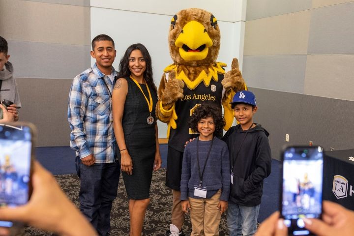 Family of four with Eddie Eagle standing while taking a photo