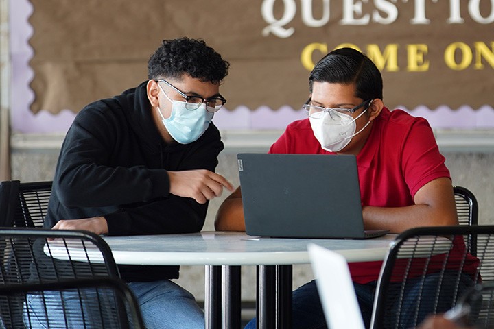 Two male students looking at a laptop at the library