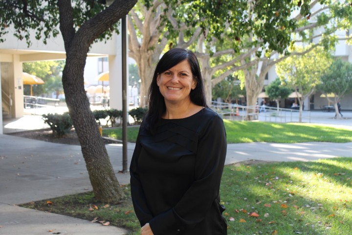 Dr. Andrea Arias standing in center of photo with grass and trees behind her