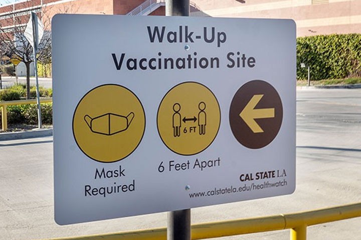 Walk-up Vaccination Site sign advises visitors to wear masks and stay 6 feet apart