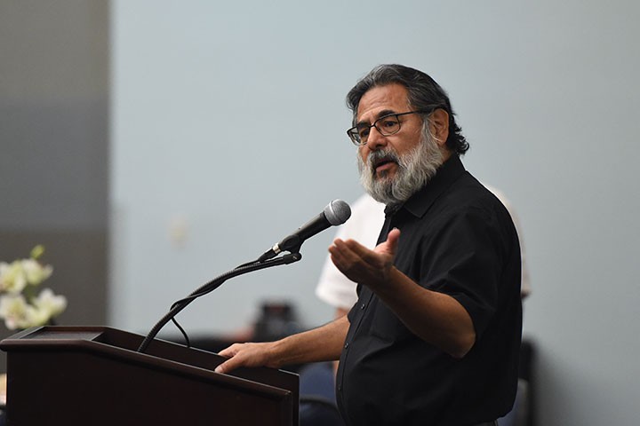 Professor in glasses speaking into microphone at lectern