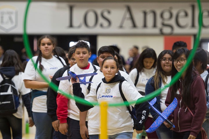 young girl aims to throw airplane through hoop on ecst open house