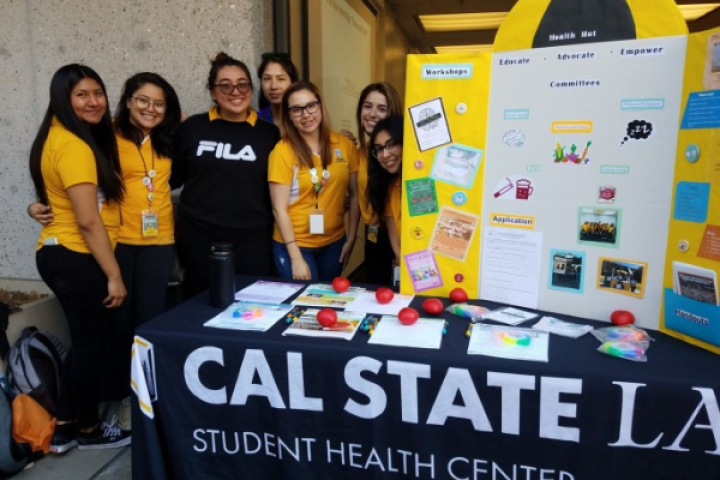 Six student interns in yellow shirts behind outreach table.