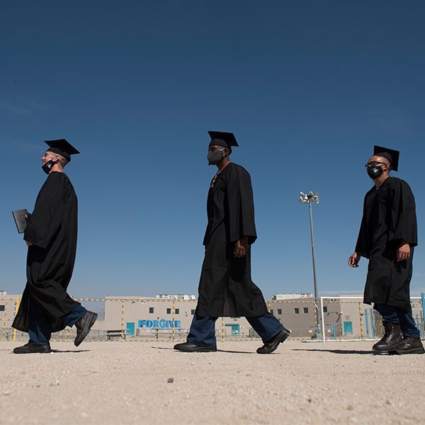 3 incarcerated individuals walking to Graduation Ceremony