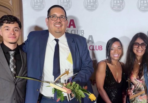Four people smile and pose with awards at an LA Press Club event in front of the organization's branded backdrop.