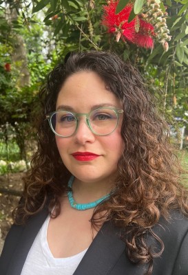 Image of Mercedes Chavez, light-skinned woman with green glasses and brown curly hair