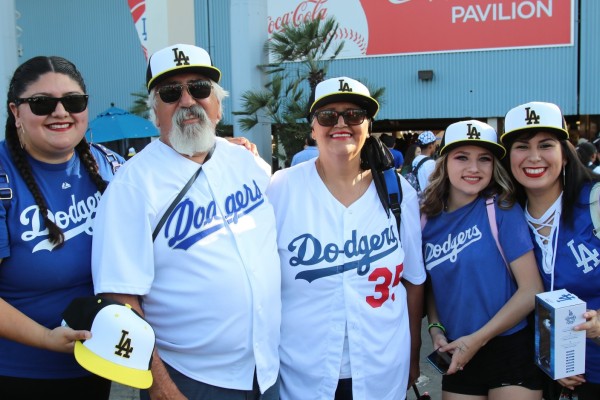 Five people posing with Cal State LA baseball caps at Dodger Stadium