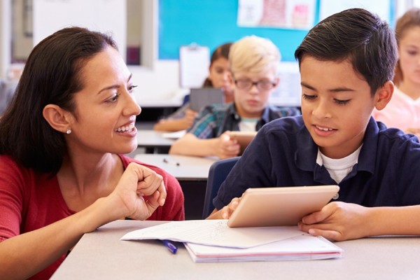 Female teacher and male student at desk.