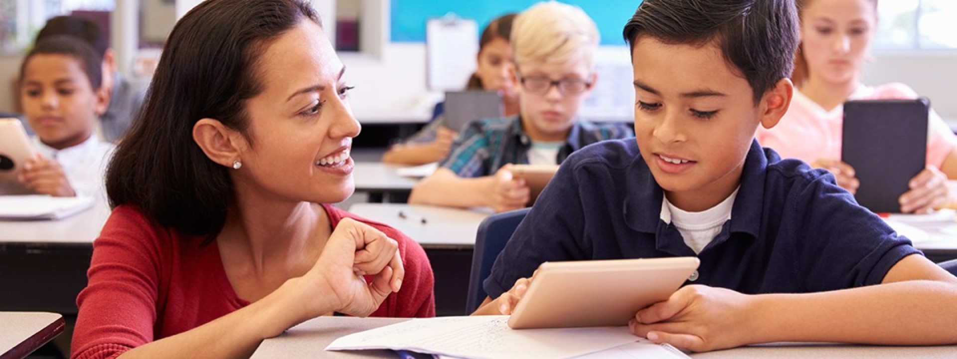 Female teacher and male student at desk.