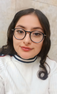 Woman with dark brown hair wearing glasses and a white sweater