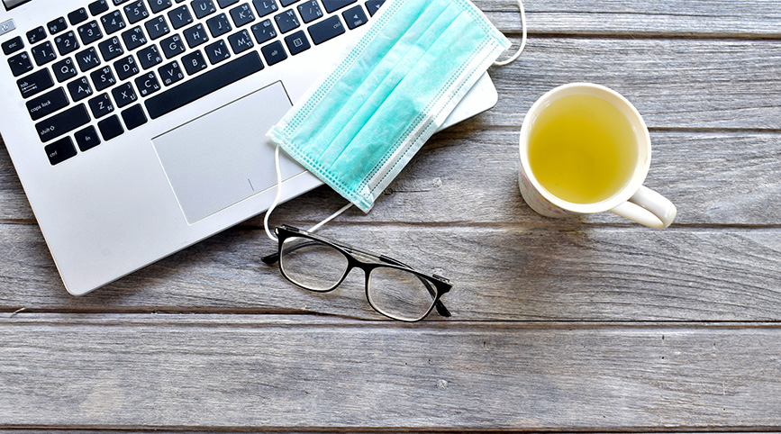 Laptop with surgical mask and a cup of tea